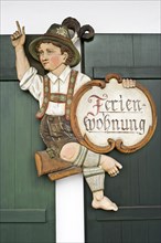 Carved wooden figure with a sign 'Ferienwohnung'