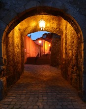 Lane passing underneath a stone archway at dusk