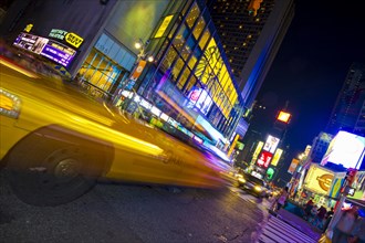 Neon signs and a taxi with motion blur in Times Square
