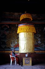 Devout Buddhist praying at a prayer wheel in Punakha Dzong