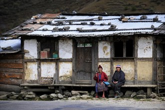Two Bhutanese women sitting in front of a small shop on the roadside