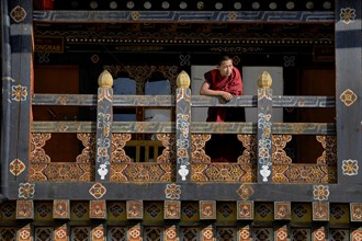 Buddhist monk leaning on a railing in Trongsa Dzong fortress