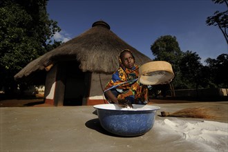 Young girl sifting flour in the village of Idool