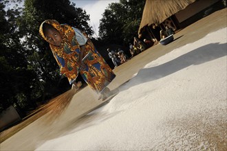 Young girl sweeping flour together on the ground in the village of Idool