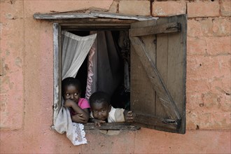 Children looking out of the window of a house