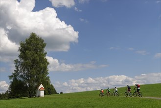 Cyclists on a bicycle tour near a small chapel