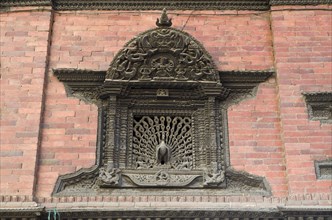 Ornate carved wooden window with a peacock sculpture