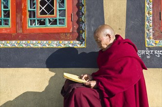 Tibetan monk reading the holy scriptures at the foot of Boudnath Stupa