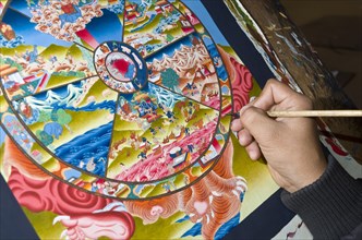 Artist painting a colorful Thangka in one of the art schools near Boudnath Stupa