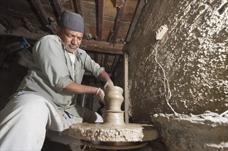 Man making pottery by hand with simple equipment