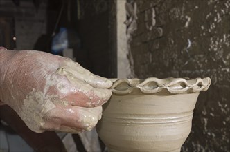 Man making pottery by hand with simple equipment