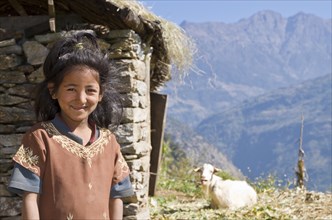 Portrait of a local girl with house and goat in the back