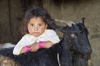 Local little girl leaning on a black goat