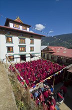 Many nuns wearing red cloths listening the teachings of Taklung Tsetru Rinpoche in the backyard of Junbesi Gompa