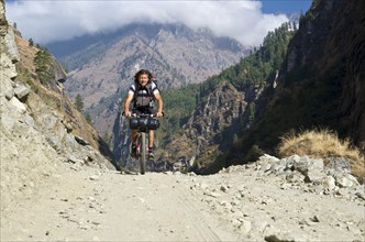 Tourist cycling on a gravel road in Marsyangdi Yuni valley