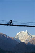 Cyclist crossing a suspension Bridge over Kali Ghandaki Valley
