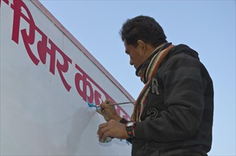 Man painting red Hindi letters on a white board