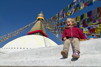 Little tourist child sitting at the foot of Boudnath Stupa