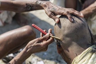 Pilgrim having his head shaved during Kumbha Mela