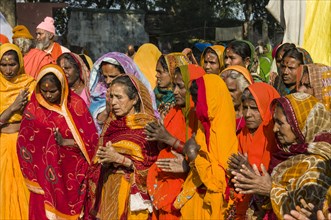 Group of colourful dressed women praying during Kumbha Mela