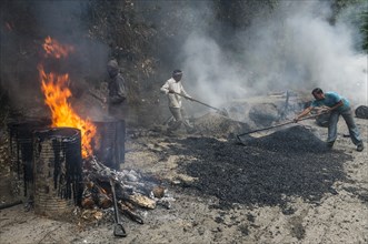 Workers applying hot asphalt to a road at a construction site