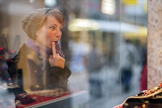 Young woman looking in the window of a jewellery store