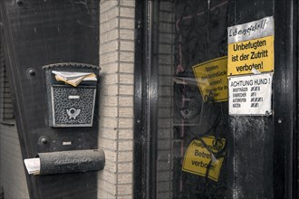 Locked front door with prohibition signs and an overflowing mailbox