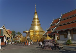 Golden chedi or pagoda with a ceremonial umbrella in the temple complex of Wat Phrathat Hariphunchai Woramahaviharn