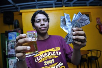 Young man in a brothel holding a beer and condoms in his hand