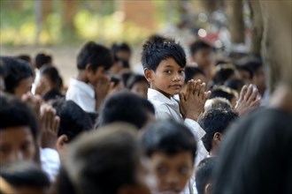 School children preparing in prayer for the donation of food and money to Buddhist monks