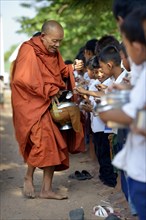 Children donating food and money to a Buddhist monk