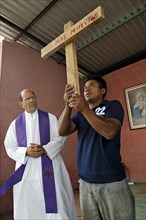A man is holding up a cross with the inscription 'No Mas Muertos'