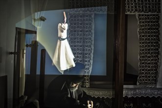 Statue of Mevlana under an holographic projection of a whirling dervish