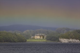Muckross House on Muckross Lake with rainbow colors in the sky