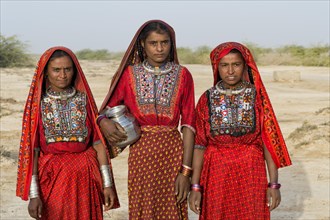 Three Fakirani women in traditional colorful clothes with a water jug