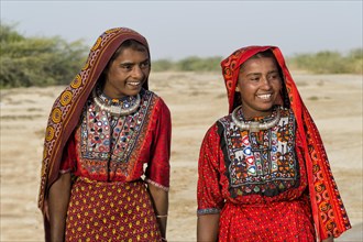 Two Fakirani women in traditional colorful clothes smiling
