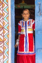 Young girl in traditional colorful clothes standing in a door