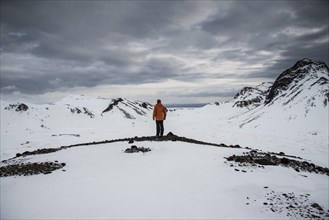 Man looking from a lookout point over a snow-covered landscape