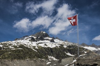 Swiss flag flying in front of Mount Galenstock from the Furka Pass with the Rhone Glacier