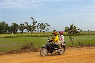 Two women riding on a motorcycle on a country road