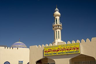 Sign of a business for household goods and electrical appliances in front of a mosque