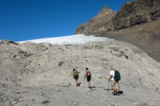 Hikers crossing the exposed bedrock of Tsanfleuron Glacier