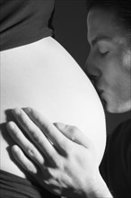 Expectant father is kissing the belly of his pregnant partner