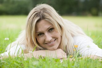 Smiling woman relaxing on her stomach in the grass
