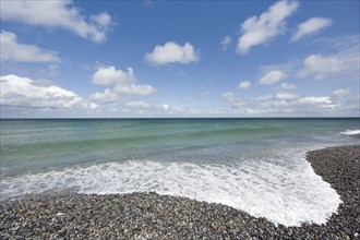 White foam of a wave on a pebble beach