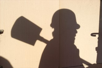 Shadow of a worker with hard hat and spade