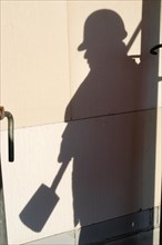 Shadow of a worker with hard hat and spade