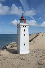 Lighthouse with the Rubjerg Knude migrating dune on the North Sea coast