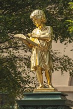 Gold plated fountain sculpture 'Boy Reading' in front of the former secondary school