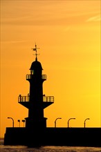 Silhouette of the Brunsbuttel Mole 1 lighthouse in front of a evening sky